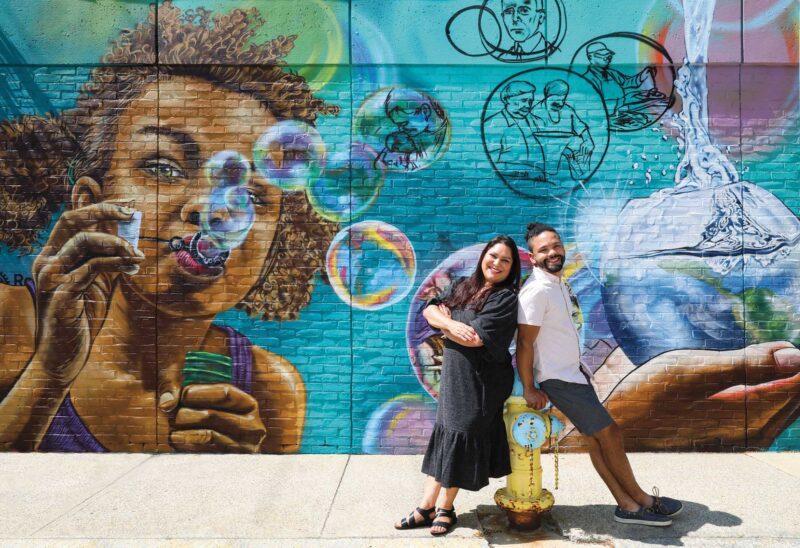 Cecilia Ulibarri and Manuel Ramirez, of Positive Street Art, in front of their mural for the Rotary Club of Nashua West on Bowers Street in Nashua. (Photo by Cheryl Senter.)