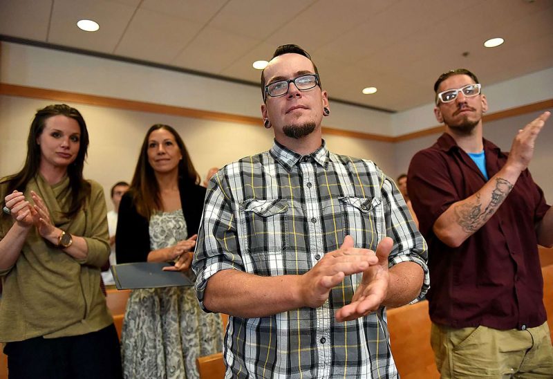 Drug Court graduates Jessica Caron (left) and Shane Crawford (in plaid) join in the applause for their fellow graduates during ceremony. (Photo courtesy of David Lane, Union Leader.)