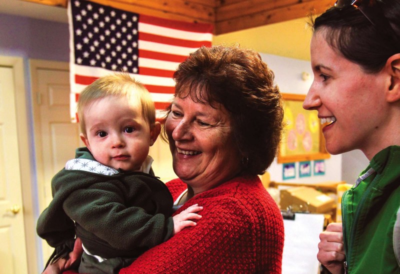 Sue Cloutier, (center) director of the White Mountains Community College Early Childhood Development Center, greets one of her youngest students. Photo by Cheryl Senter.